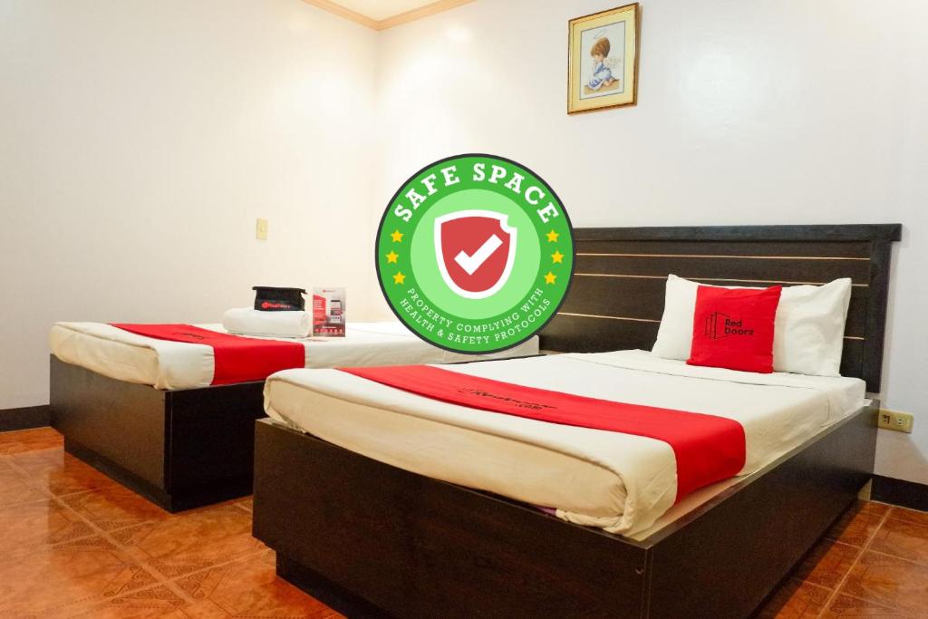 2 camas en una habitación con un cartel en la pared en RedDoorz near Maribago Barangay Hall en Isla de Mactán