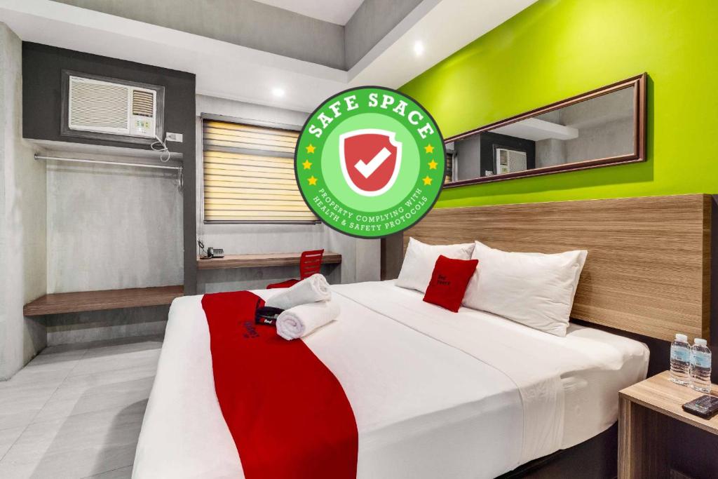 a hotel room with a bed with a green sign on it at RedDoorz Plus @ Jones Avenue Cebu in Cebu City