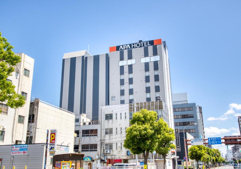 a building with a hotel sign on top of it at APA Hotel Marugame Ekimaeodori in Marugame
