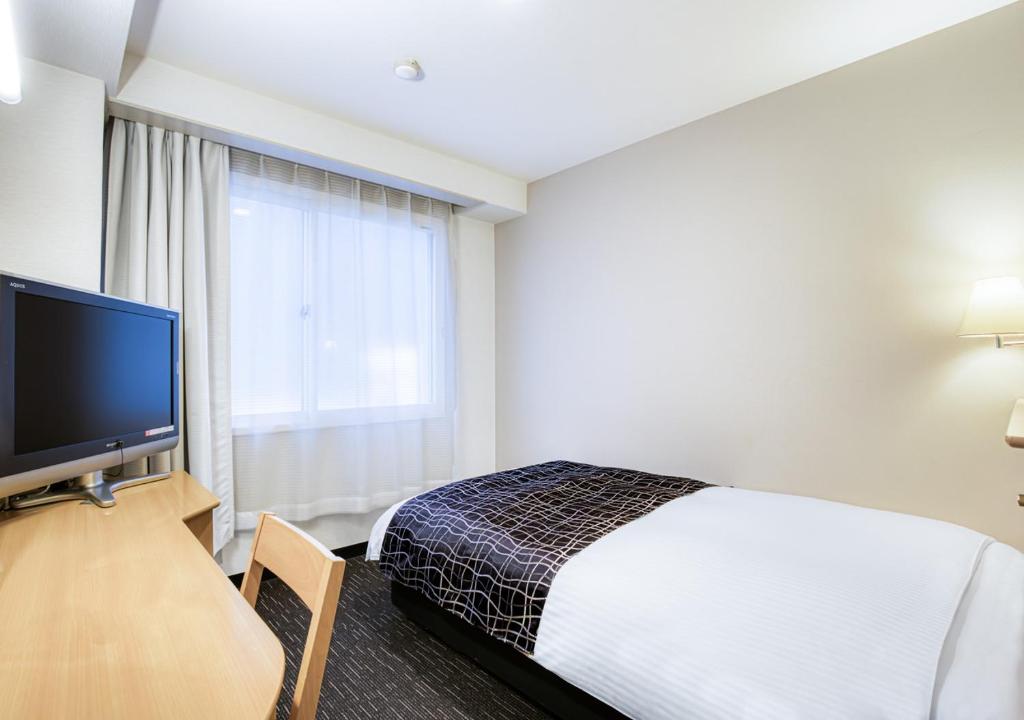a hotel room with a bed and a flat screen tv at APA Hotel Marugame Ekimae Odori in Marugame
