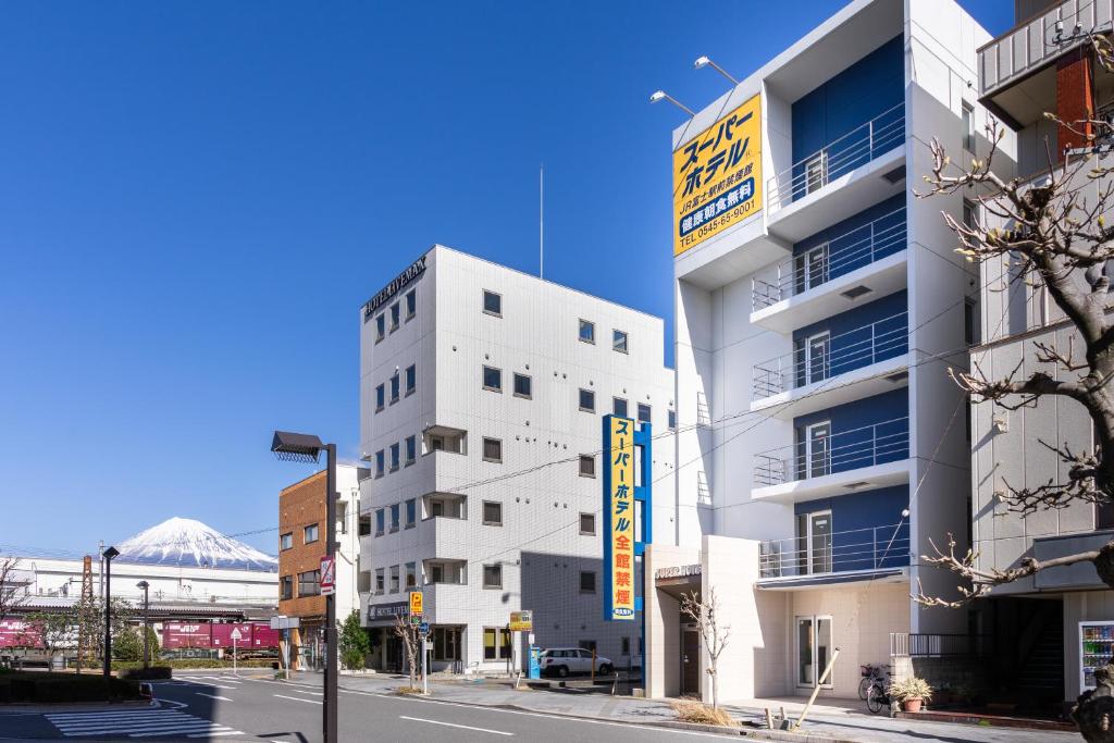 富士的住宿－Super Hotel JR Fujiekimae Kinenkan，白色的建筑,旁边标有标志
