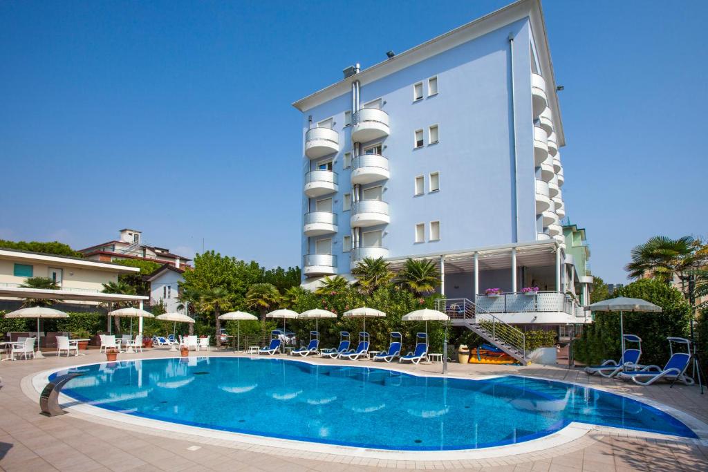 un hotel con piscina frente a un edificio en Hotel Helios en Lido di Jesolo