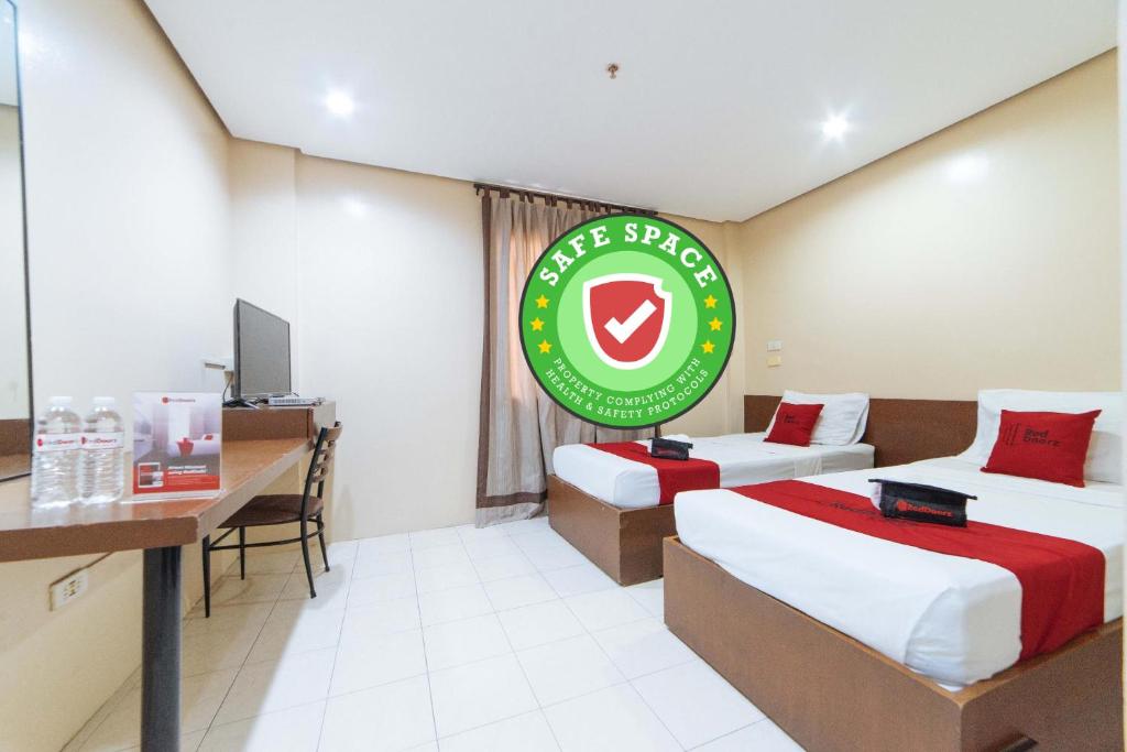 ein Hotelzimmer mit 2 Betten, einem Schreibtisch und einem Schild in der Unterkunft RedDoorz near Olongapo Bus Terminal in Olongapo
