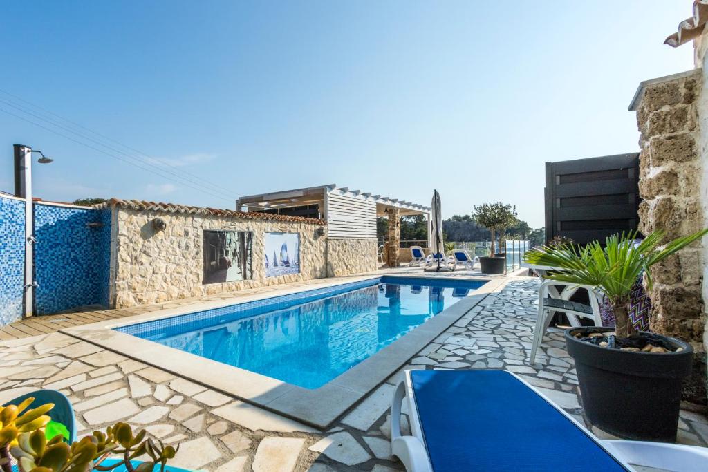 a swimming pool with blue chairs and a house at Bluesun Sibenik Apartments in Šibenik