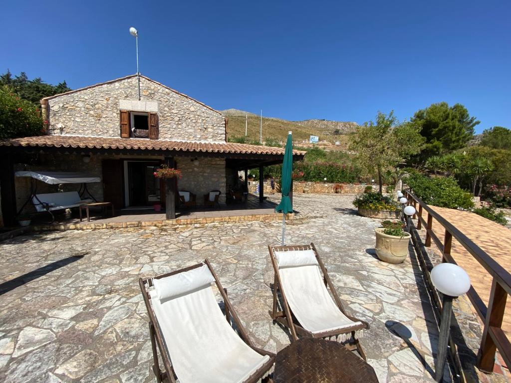 un patio avec deux chaises et un bâtiment dans l'établissement Casale Giulietta, à Scopello