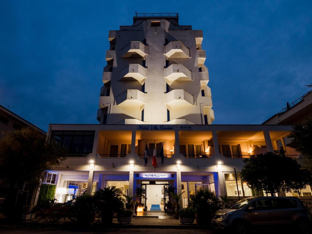 een wit gebouw met 's nachts een toren bij Hotel Villa Sorriso in Senigallia