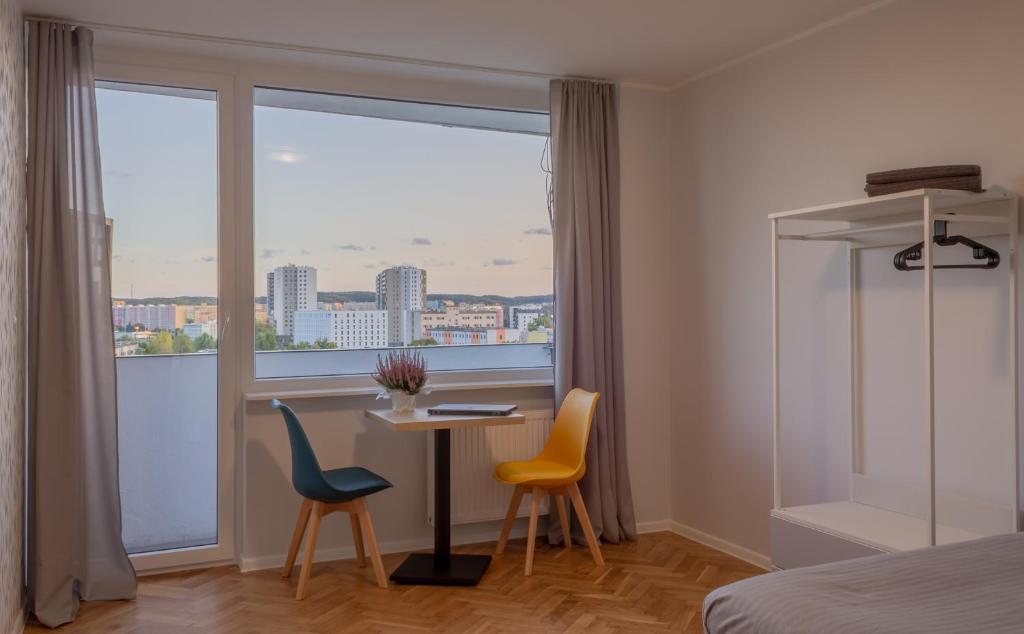 um quarto com uma mesa, 2 cadeiras e uma janela em INITIUM rooms - Pokoje na wynajem - Obrońców Wybrzeża 4D em Gdansk