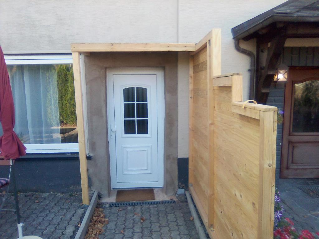 einem Holzschuppen mit einer Tür und einem Zaun in der Unterkunft Ferienappartement Studio " Michel" Otzenhausen in Nonnweiler