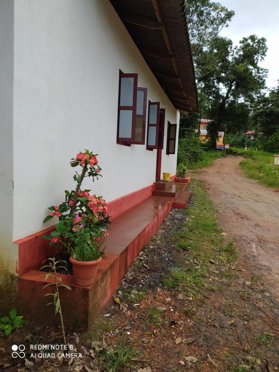 a porch of a house with flowers on it at VANASIRI COTTAGE (Tourist Home) in Dharmastala