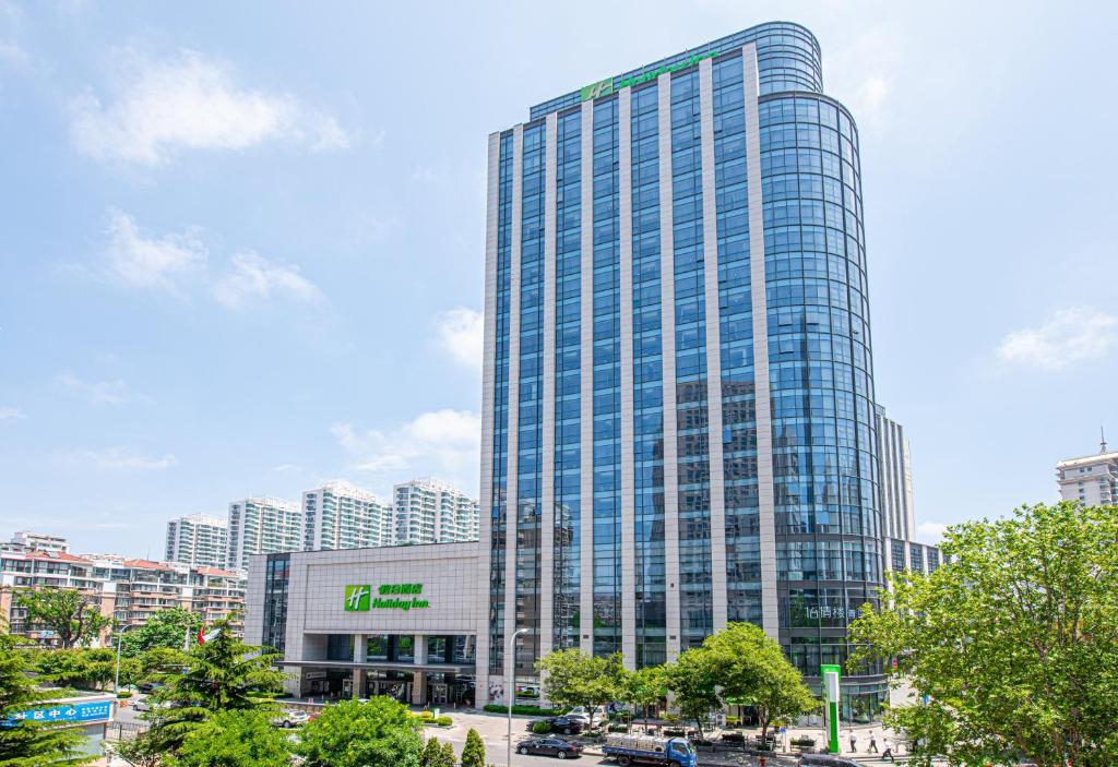 wysoki szklany budynek w mieście z budynkami w obiekcie Holiday Inn Qingdao City Center, an IHG Hotel - May 4th Square w mieście Qingdao