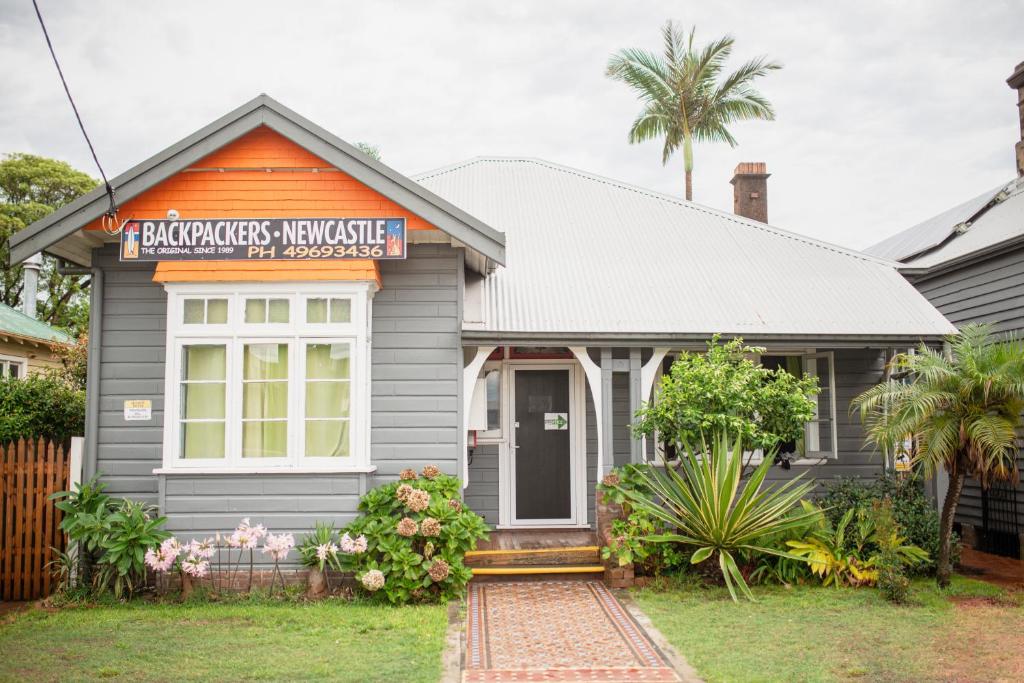 a gray house with a sign on the front of it at Backpackers Newcastle in Newcastle