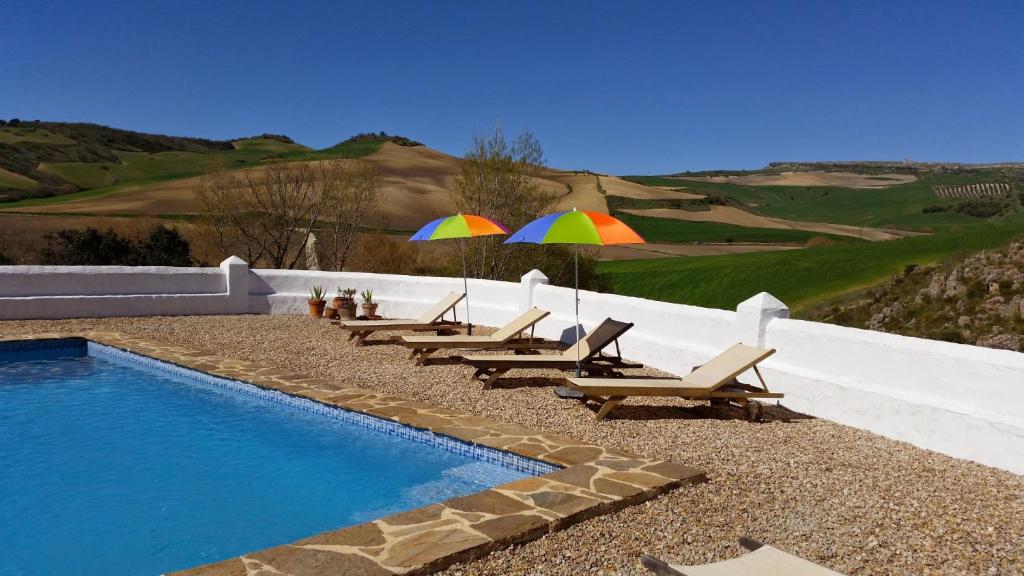 a group of chairs and umbrellas next to a swimming pool at Beautiful Cortijo with pool near Ronda in Ronda