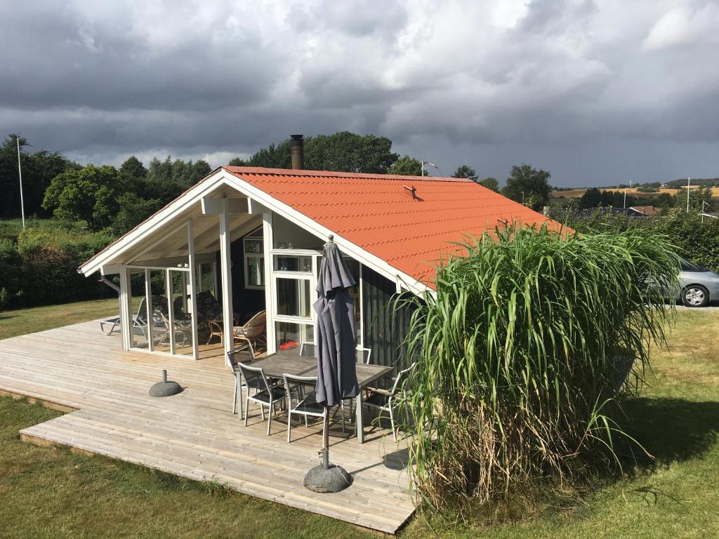 una pequeña casa con techo naranja en una terraza de madera en Two-Bedroom Holiday Home for 6 in Vemmingbund, en Broager
