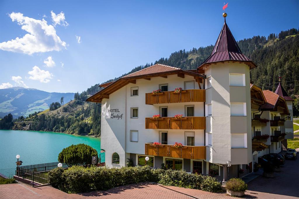 a hotel with a view of a lake and mountains at Hotel Seehof in Monguelfo