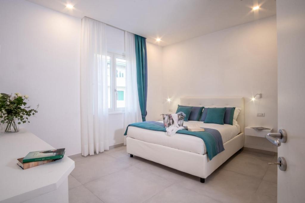a white bedroom with a bed and a window at LEONE ROSSO APARTMENTs in Sorrento