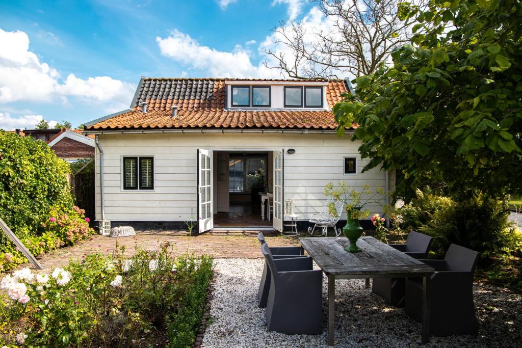 a small white house with a table and chairs at Gastenverblijf KortVertoef in Kortenhoef
