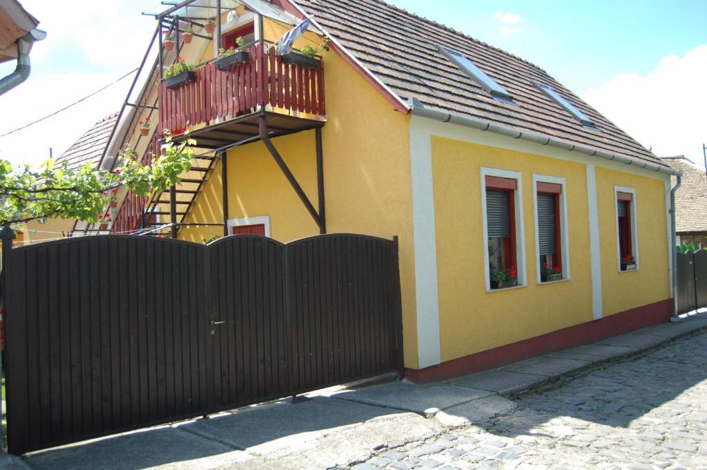 Casa amarilla con valla y balcón en Zách Klára utcai Apartman, en Visegrád