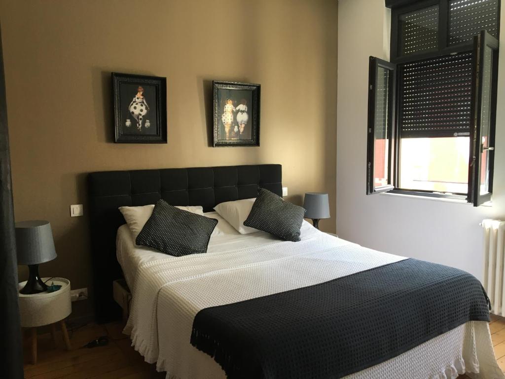 a bedroom with a black and white bed with pillows at Les terrasses de l’orchestre in Amiens