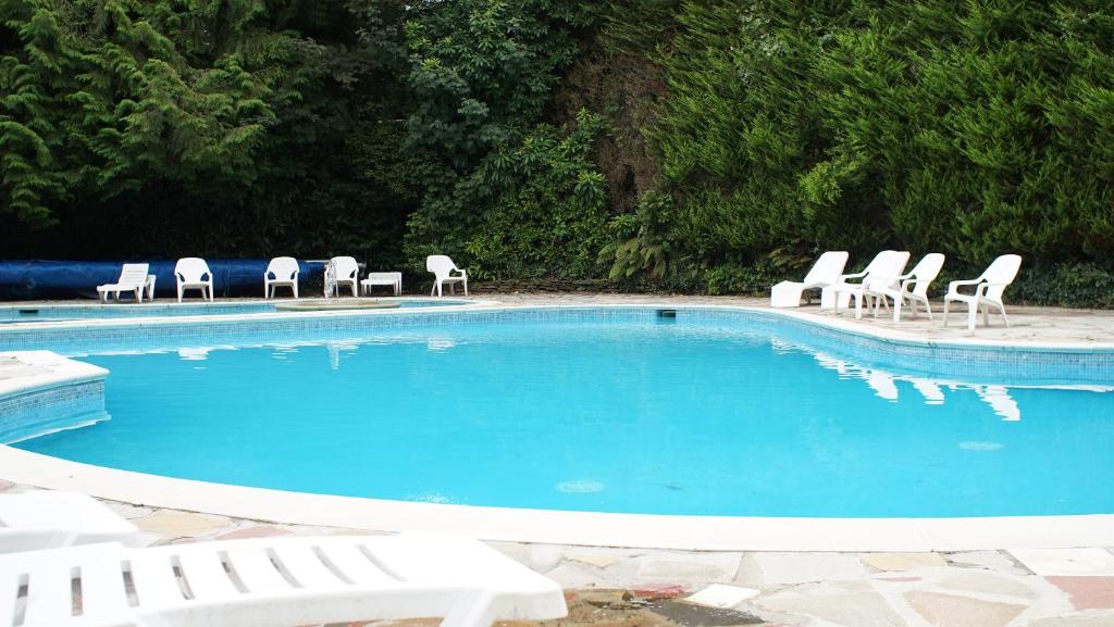 a swimming pool with white chairs and a group at Holiday home, Camelford, Cornwall in Camelford