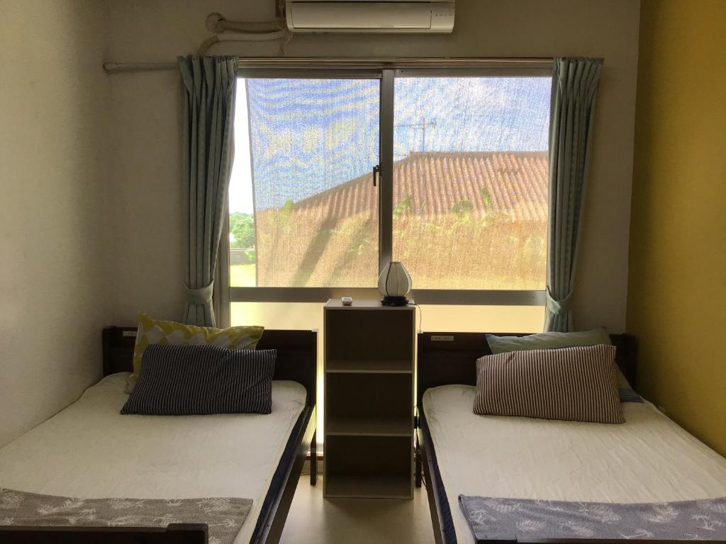 two beds in a room with a large window at Shimaotoya in Iriomote