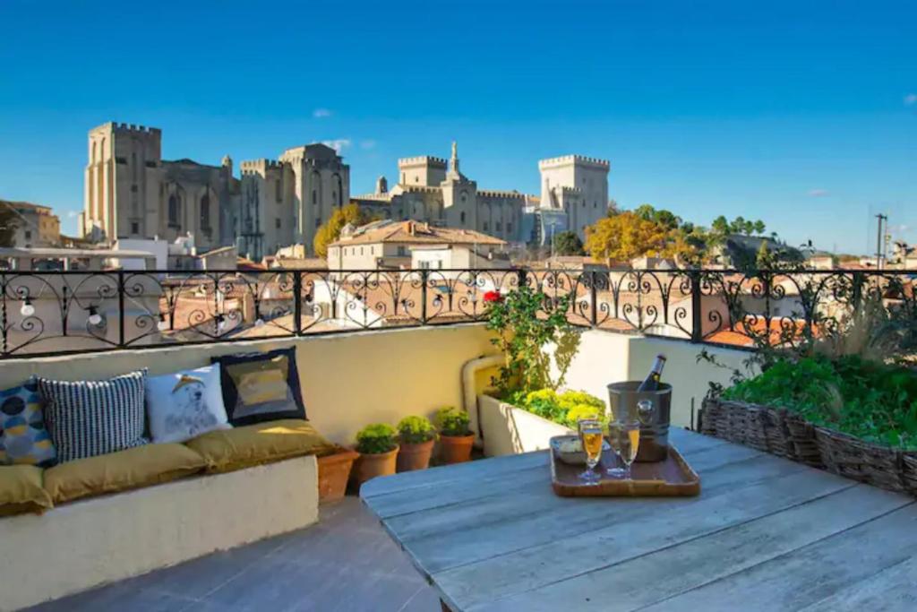 d'un balcon avec une table et une vue sur la ville. dans l'établissement MAGNIFIQUE APPARTEMENT DE CHARME AVEC VUE SUR LE PALAIS DES PAPES À AVIGNON WiFI GRATUIT, à Avignon
