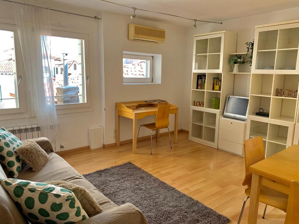 Una sala de estar con un sofá, una mesa y un escritorio. en REGINA - ROMANTIC STUDIO near RIALTO, en Venecia