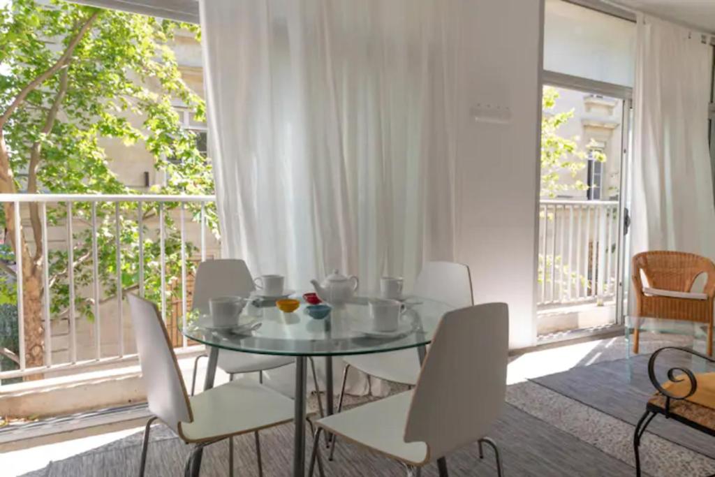 une salle à manger avec une table en verre et des chaises blanches dans l'établissement GRAND APPARTEMENT LUMINEUX POUR 2 à 4 PERSONNES A AVIGNON INTRA-MUROS WiFI GRATUIT, à Avignon