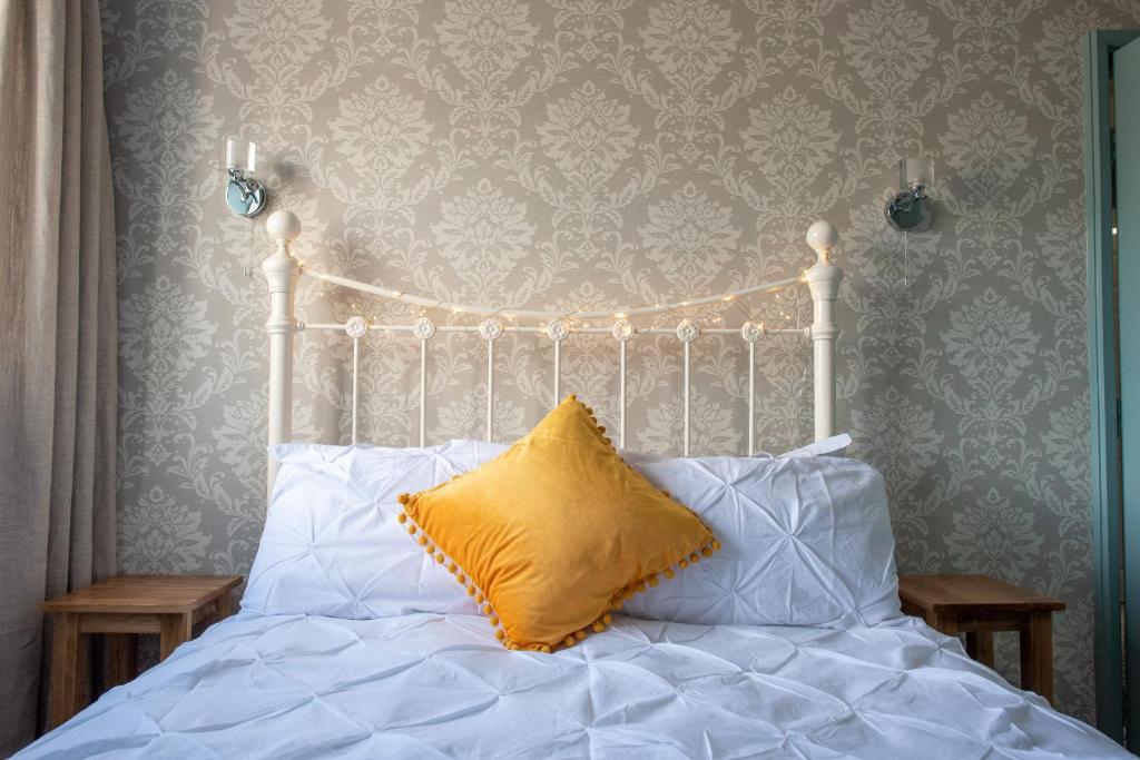 Una cama blanca con una almohada amarilla. en Clovelly Guest House en Lyme Regis
