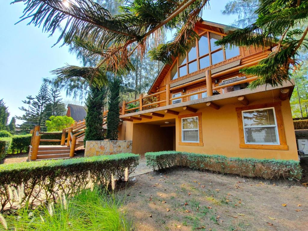 une maison avec un palmier en face dans l'établissement Toscana Log Home, à Ban Nong Rua