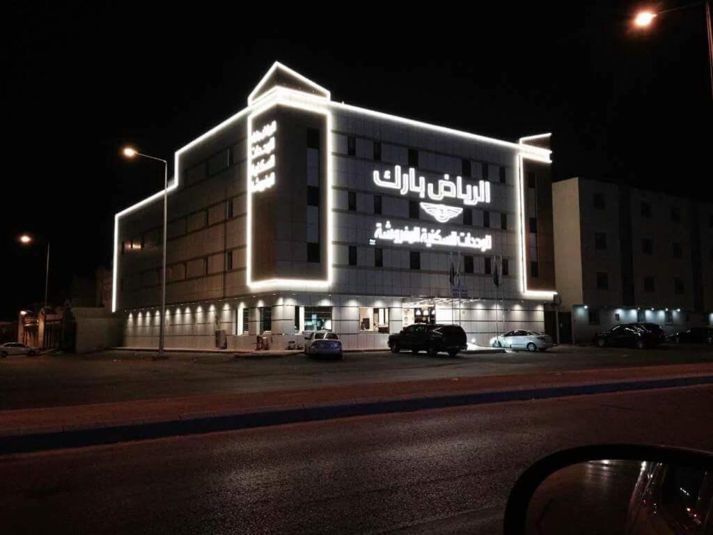 a large building with a sign on it at night at الرياض بارك للاجنحة الفندقية in Riyadh