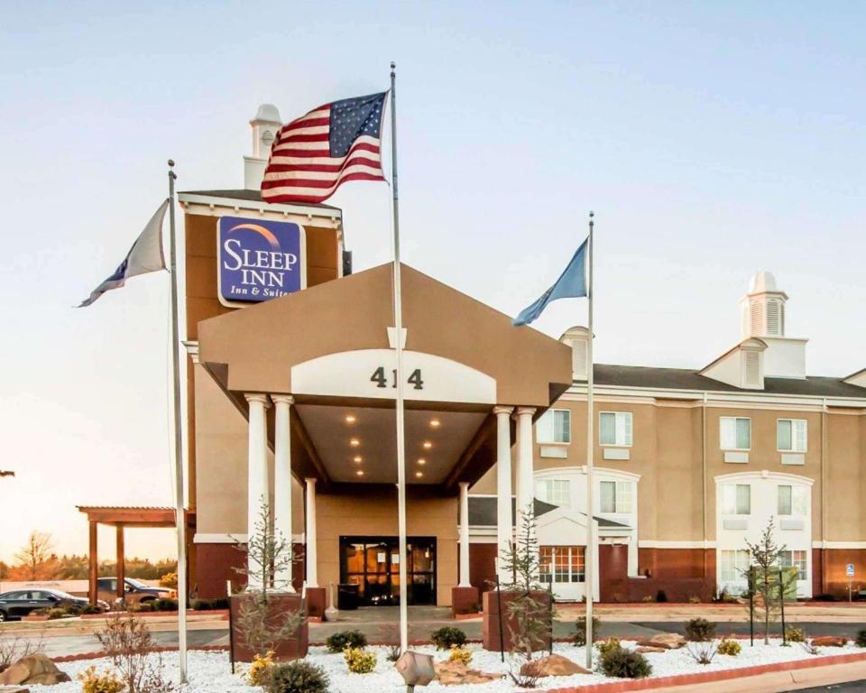 a hotel with an american flag in front of it at Sleep Inn & Suites Guthrie - Edmond North in Guthrie