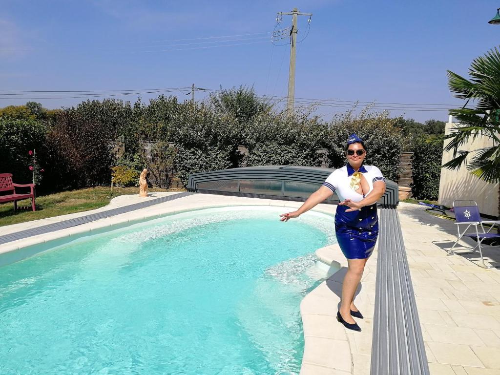 a woman holding a baby standing next to a swimming pool at lamaison-d'ose in Romans