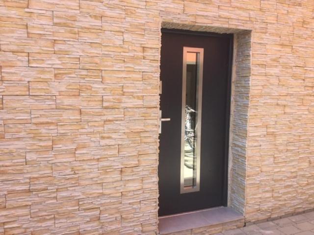 a brick wall with a black door on a building at Bungalow am Donaupark in Regensburg