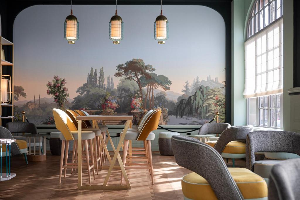 ein Restaurant mit Stühlen, einem Tisch und einem Wandbild in der Unterkunft Grand Hôtel Bristol in Colmar