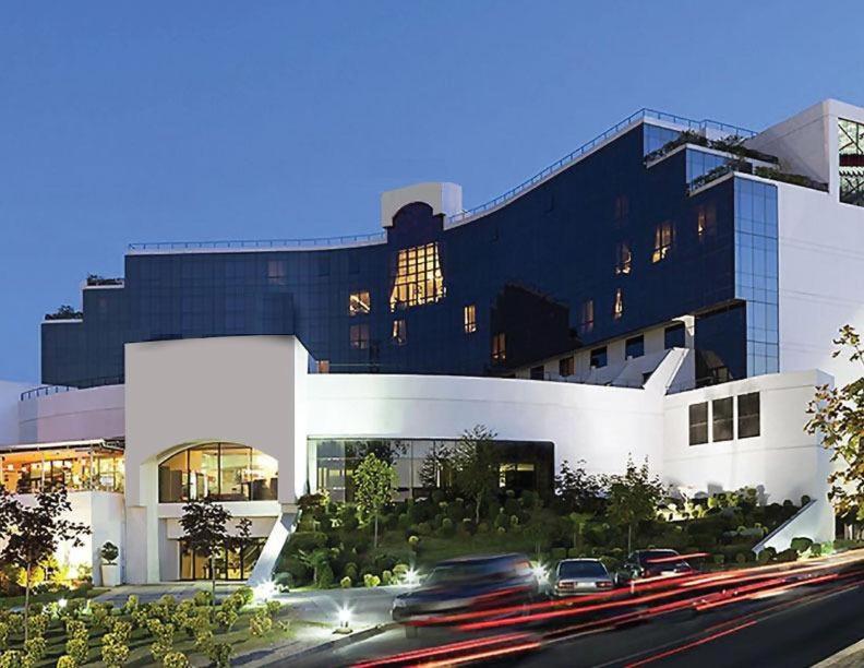 a building with cars driving past it on a street at Mak Albania Hotel in Tirana