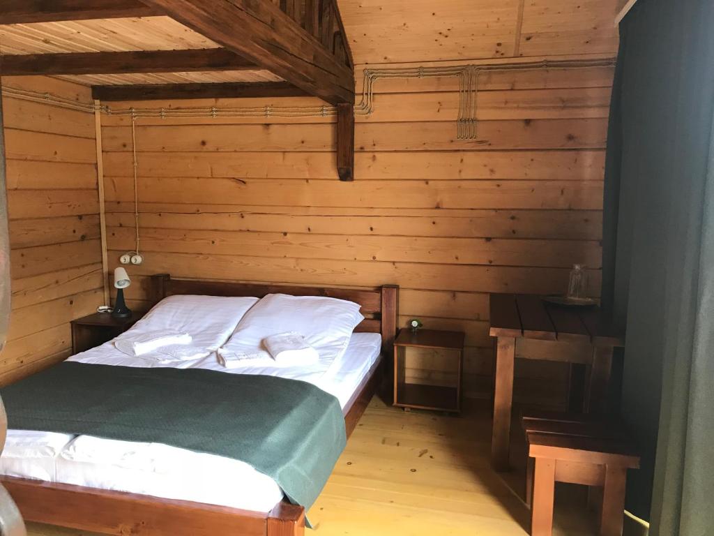 1 dormitorio con 1 cama en una cabaña de madera en Готельний комплекс БУДИНОК РИБАКА, en Sataniv