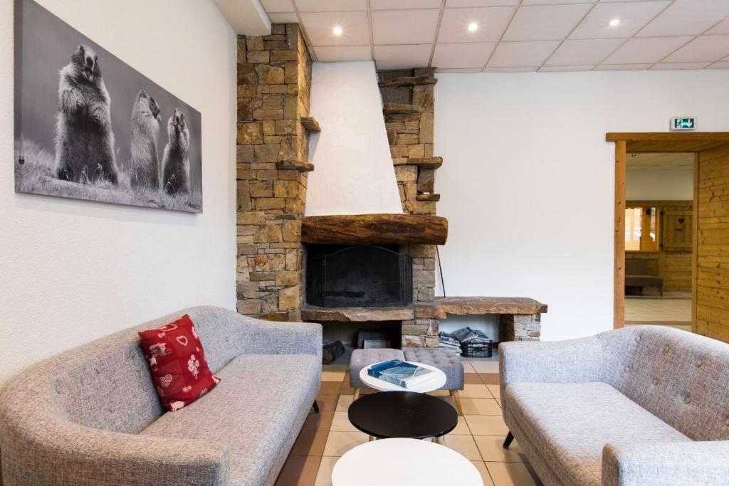 a living room with two couches and a stone fireplace at Village Vacances le Bérouze in Samoëns