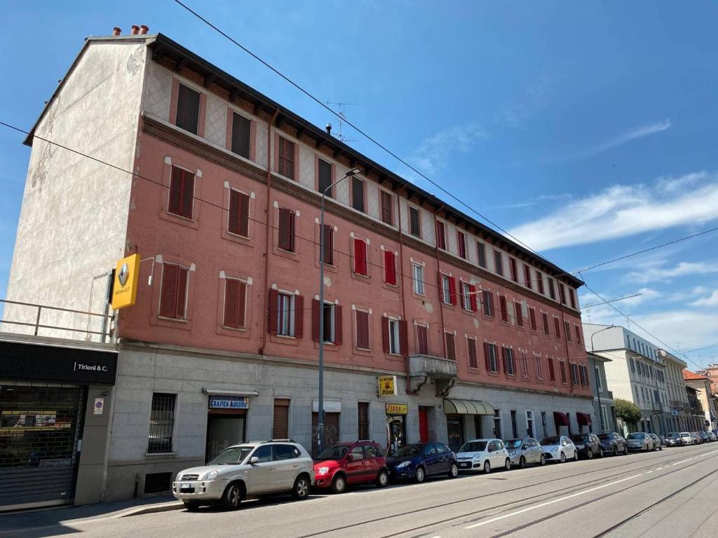 un grande edificio in mattoni su una strada di città con auto parcheggiate di Milano Via Ripamonti IEO a Milano