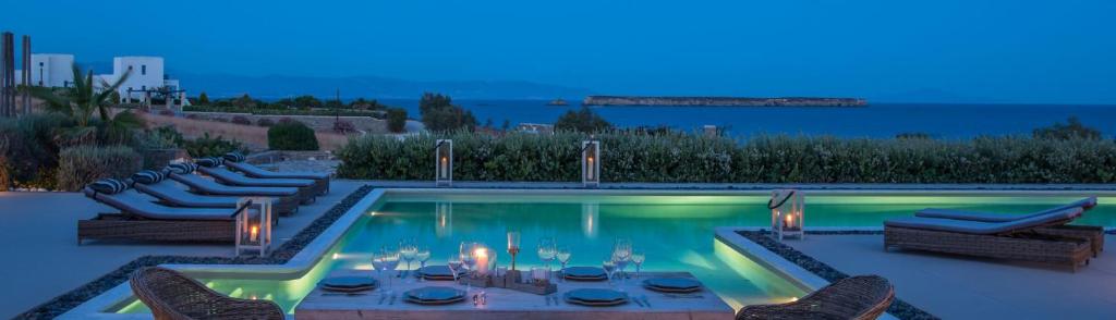 una piscina con mesa y sillas y el océano en Luxury Paros Villa Superior Villa Private Pool Stunning Interior 7 BDR Tserdakia en Kampos Paros