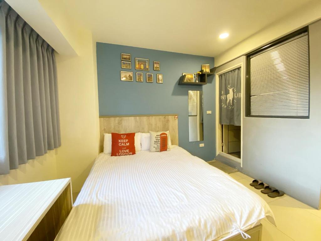 - une chambre avec un lit doté de draps blancs et d'oreillers orange dans l'établissement Day Day Fengjia, à Taichung