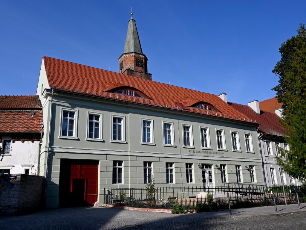 un gran edificio blanco con techo rojo en Hotel Brandenburger Dom, en Brandenburg an der Havel