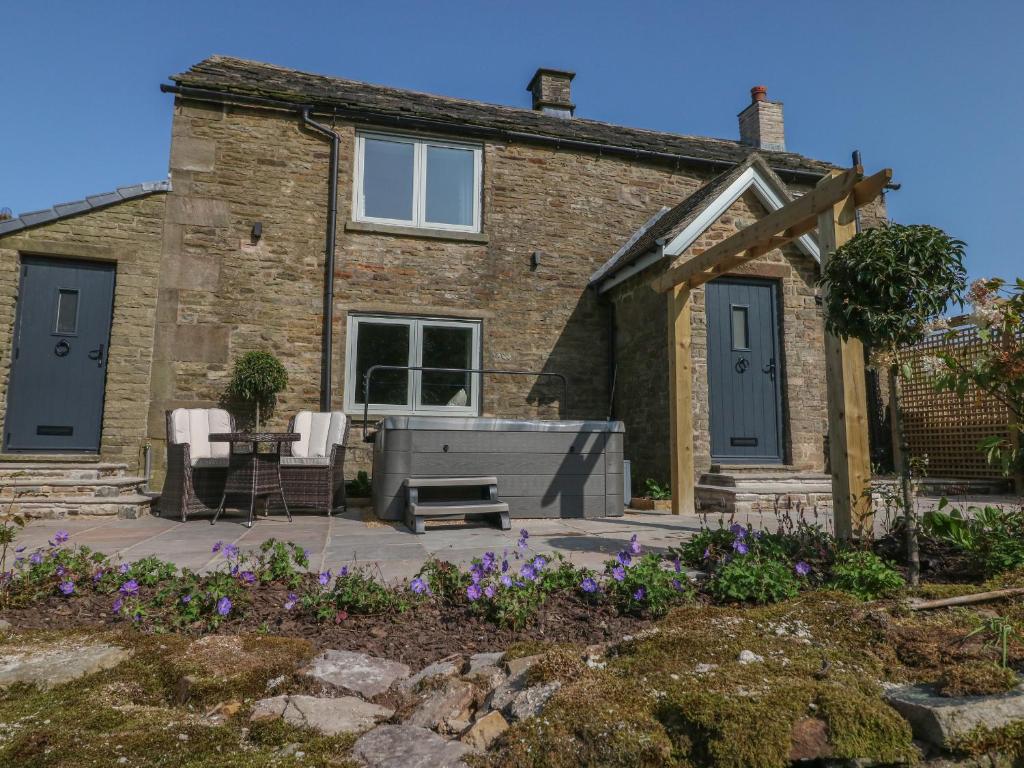 ein Steinhaus mit einer Terrasse, einem Tisch und Stühlen in der Unterkunft Overlea Cottage in Highpeak Junction