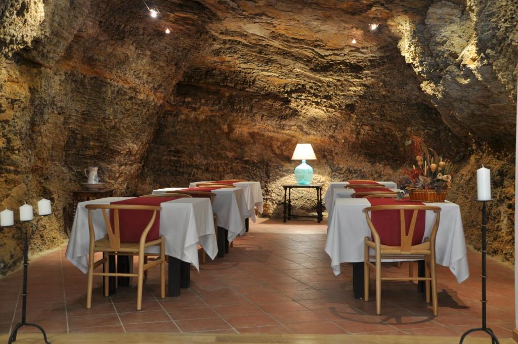 uma sala de jantar numa caverna com mesas e cadeiras em Hotel Cervaria em Cervera del Río Alhama