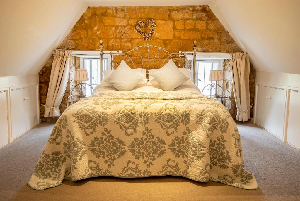 a bedroom with a large bed with a stone wall at The Burrow in Chideock