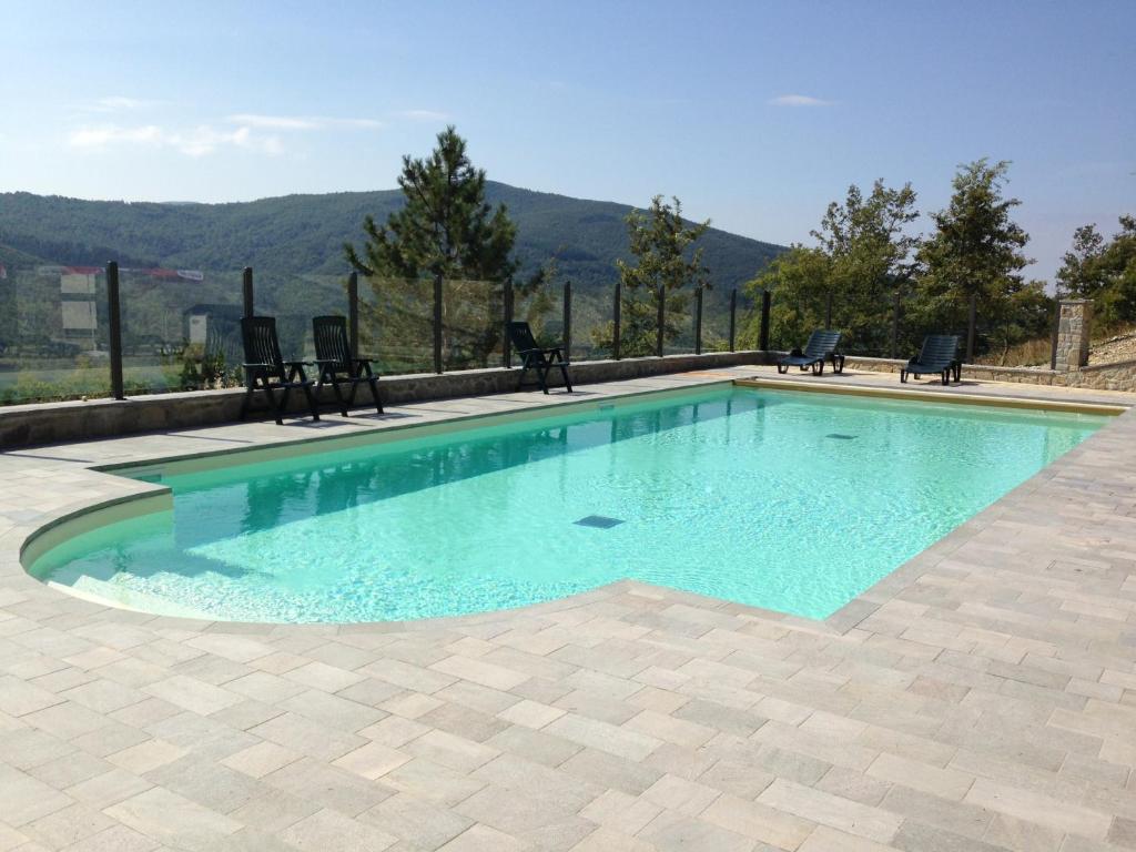 a swimming pool with chairs and a view of the mountains at Villa La Verna in Chiusi della Verna