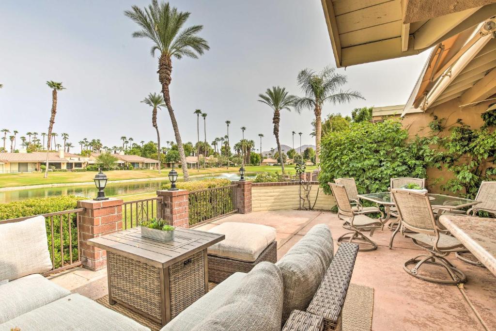 a patio with chairs and tables and palm trees at Upscale Palm Desert Escape with Patio and Shared Pool! in Palm Desert