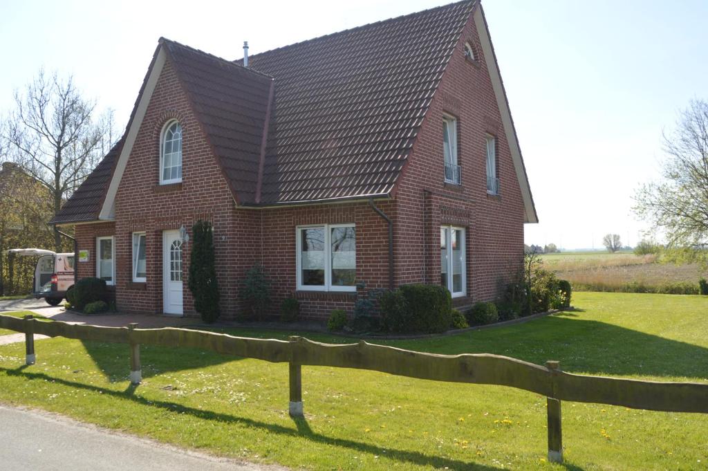 una casa de ladrillo rojo con una valla delante de ella en Ferienhaus Tini, en Wirdum