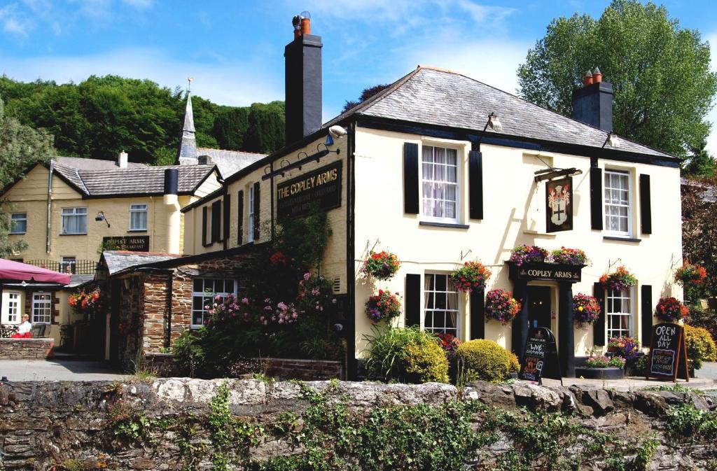 a white house with flowers in front of it at The Copley Arms in East Looe