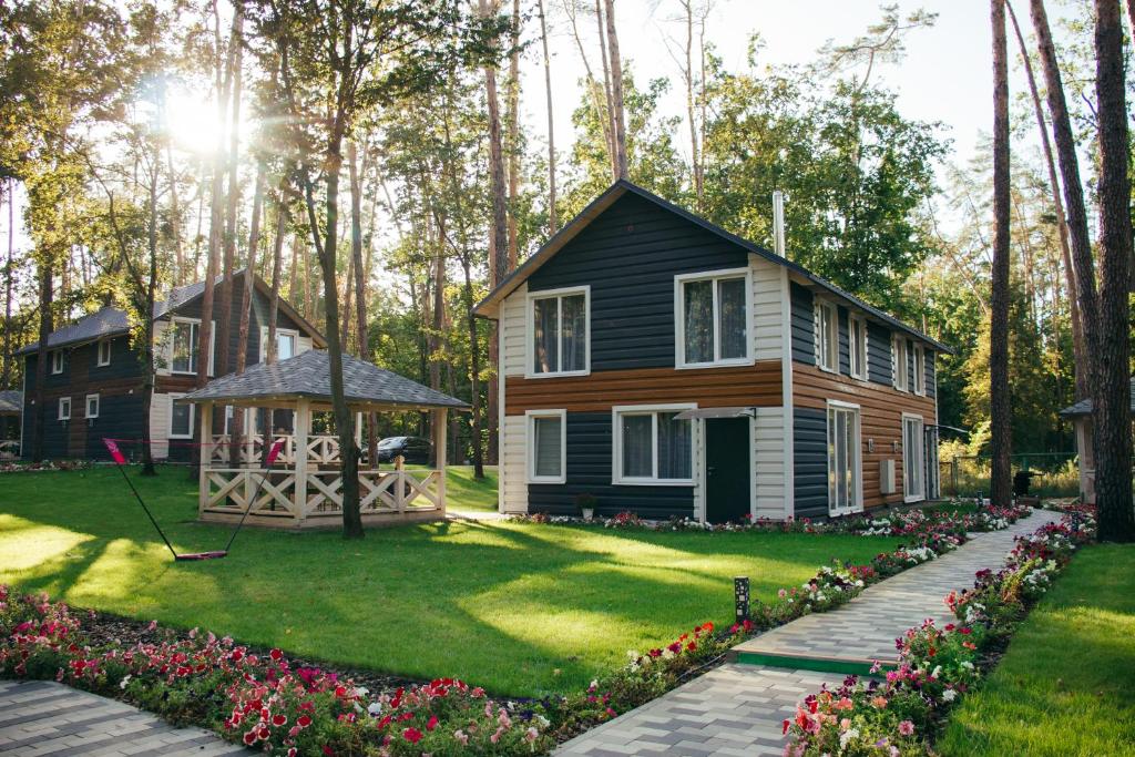 ein Haus mit einem Garten mit Blumen und einem Pavillon in der Unterkunft Клуб відпочинку Dacha in Sokirno