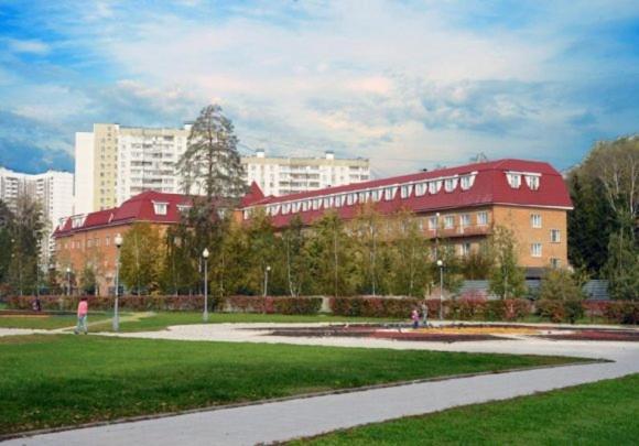 un gran edificio con techo rojo en un parque en Record Hotel, en Zelenograd